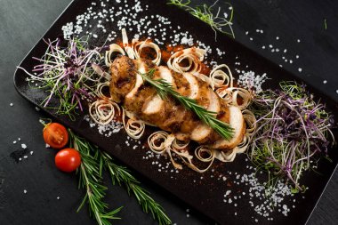 Siyah arka planda ızgara tavuk eti madalyonu.