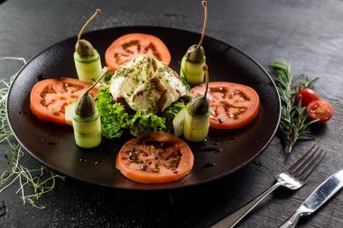 Keçi peynirinden bir tabak ve siyah sebze.