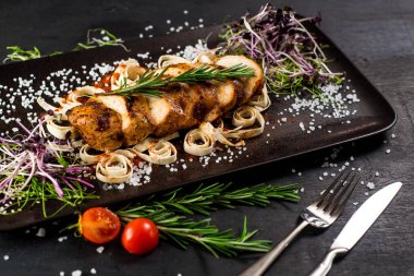 Siyah arka planda ızgara tavuk eti madalyonu.