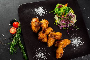 Siyah arka planda sebzeli kızarmış tavuk budu.