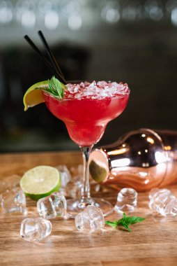 Kırmızı bir kokteyl, arka planda cam ile doğranmış buz.