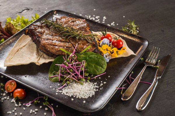 Grilled marble steak dish on black background