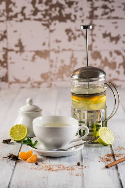 Fruit green tea in a cupand teapot on the wooden background