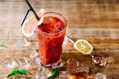 Kanlı Mary adında kırmızı bir kokteyl. Tahtada buzlu cam var.