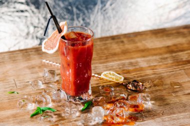 Kanlı Mary adında kırmızı bir kokteyl. Tahtada buzlu cam var.