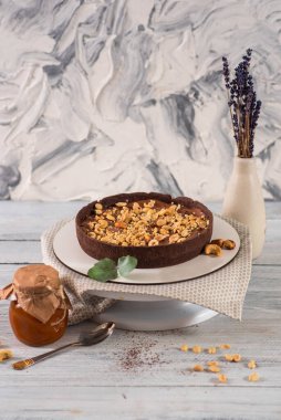 Fıstıklı çikolatalı tart ve beyaz ahşap arka planda karamel.