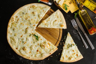 Siyah arka planda farklı peynirli bir pizza.