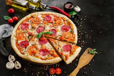 Siyah arka planda salamlı ve peynirli lezzetli pizza.