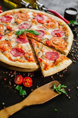 Siyah arka planda salamlı ve peynirli lezzetli pizza.