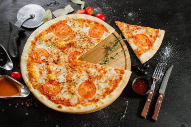 Çift peynirli lezzetli pizza ve siyah arka planda domates.