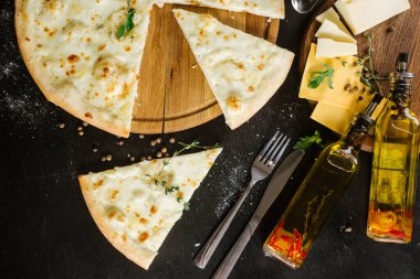 Siyah arka planda farklı peynirli bir pizza.