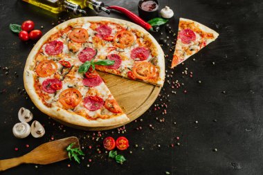 Siyah arka planda salamlı ve peynirli lezzetli pizza.