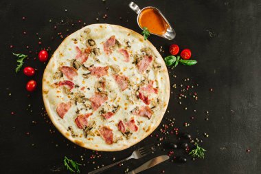 Siyah arka planda çeşitli malzemelerle lezzetli etli pizza.