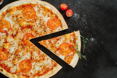 Çift peynirli lezzetli pizza ve siyah arka planda domates.