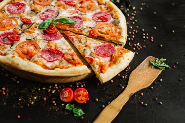 Siyah arka planda salamlı ve peynirli lezzetli pizza.