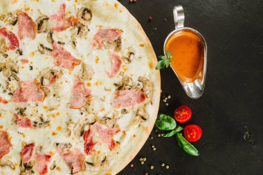 Siyah arka planda çeşitli malzemelerle lezzetli etli pizza.