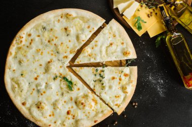 Siyah arka planda farklı peynirli bir pizza.