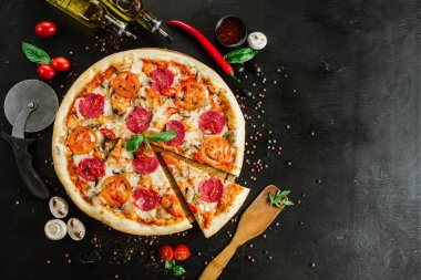 Siyah arka planda salamlı ve peynirli lezzetli pizza.
