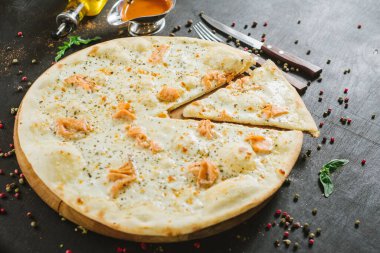 Siyah arka planda somon pizzası.