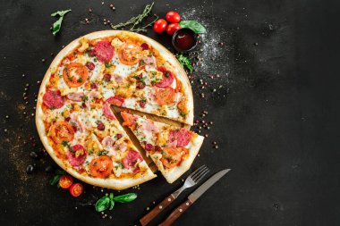 Siyah arka planda salamlı ve jambonlu pizza.