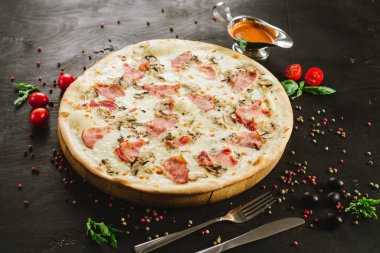 Siyah arka planda çeşitli malzemelerle lezzetli etli pizza.