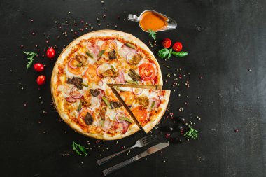 Siyah arka planda çeşitli malzemelerle lezzetli etli pizza.