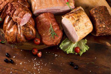 Ahşap zemin üzerinde baharat ve otlarla farklı tütsülenmiş et kompozisyonu