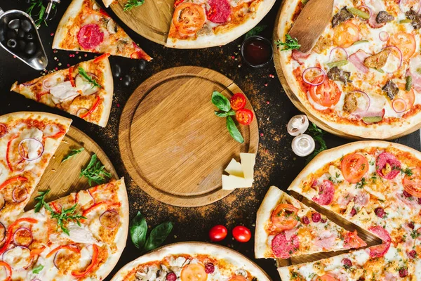 Many kinds of tasty pizzas on black background. Flatlay. Copy space