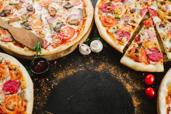 Many kinds of tasty pizzas on black background. Flatlay. Copy space