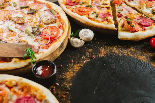 Many kinds of tasty pizzas on black background. Flatlay. Copy space