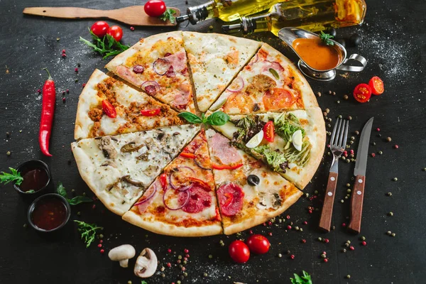 Farklı pizza parçaları siyah üzerine büyük bir pizza koyun.