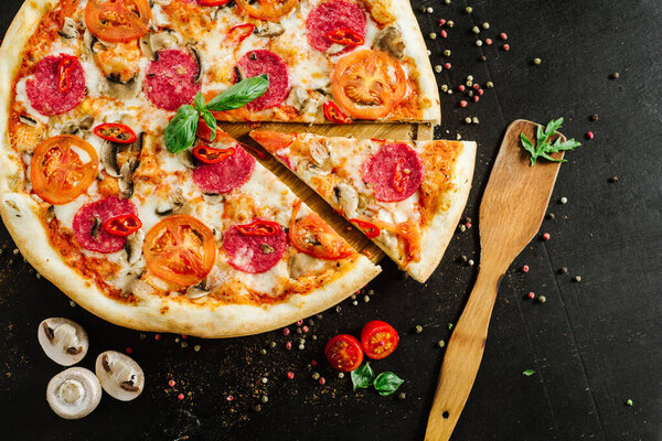 Tasty pizza with salami and cheese on black background