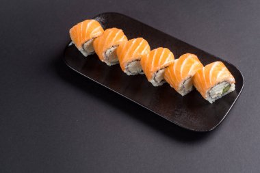 Suşi rulolarını siyah bir tabakta kapatıyorlar.