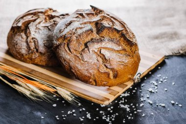 Siyah ahşap arka planda taze ekmek ve buğday.