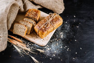 Siyah ahşap zemin üzerinde tatlı çavdar ekmeği ve buğday