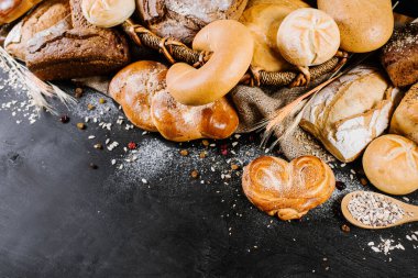 Siyah ahşap arka planda pek çok çeşit fırın ve ekmek var.