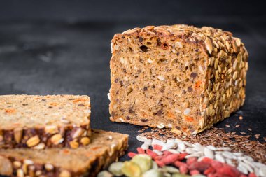 Siyah ahşap arka planda tohumlu tatlı çavdar ekmeği.