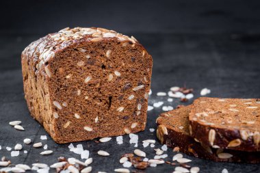 Siyah ahşap arka planda tohumlu tatlı çavdar ekmeği.