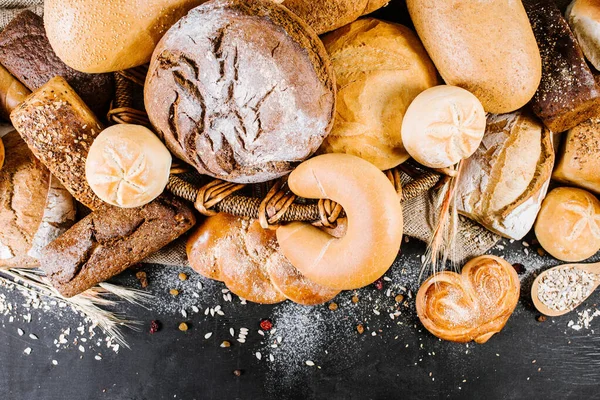 Many different kinds of bakery and bread on black wooden background