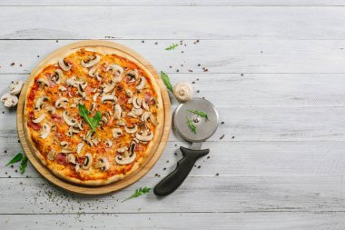 Beyaz ahşap arka planda domates soslu, jambonlu ve şampiyonlu lezzetli pizza Caprizzioza.