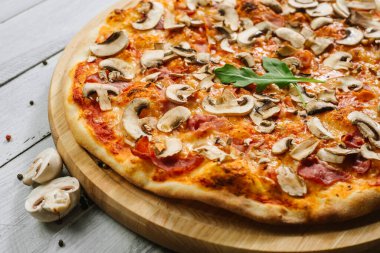 Beyaz ahşap arka planda domates soslu, jambonlu ve şampiyonlu lezzetli pizza Caprizzioza.