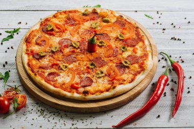 Beyaz ahşap arka planda mozzarella, salam, biber ve zeytinli pizza.