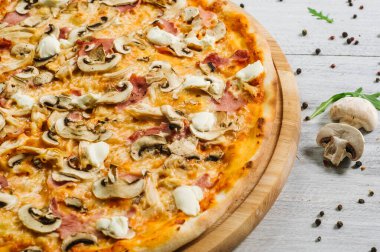Mozarella, mırıldanma, tavuk filetosu ve beyaz ahşap arka planda şampanyalar olan lezzetli bir pizza.