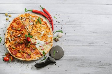 Farklı pizza çeşitlerinde dilimler, ahşap arka planda yuvarlak bir parça halinde.