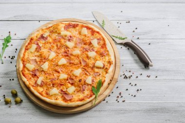 Beyaz ahşap arka planda domates soslu ve ananaslı lezzetli Hawaii pizzası.