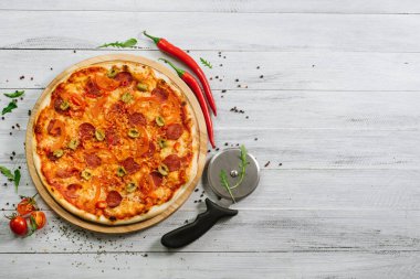 Beyaz ahşap arka planda mozzarella, salam, biber ve zeytinli pizza.
