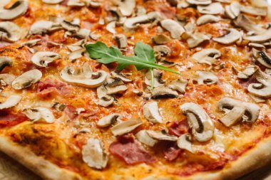 Beyaz ahşap arka planda domates soslu, jambonlu ve şampiyonlu lezzetli pizza Caprizzioza.