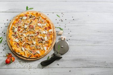 Mozarella, mırıldanma, tavuk filetosu ve beyaz ahşap arka planda şampanyalar olan lezzetli bir pizza.