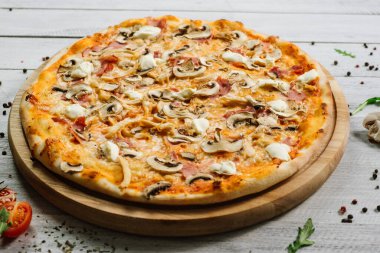 Mozarella, mırıldanma, tavuk filetosu ve beyaz ahşap arka planda şampanyalar olan lezzetli bir pizza.