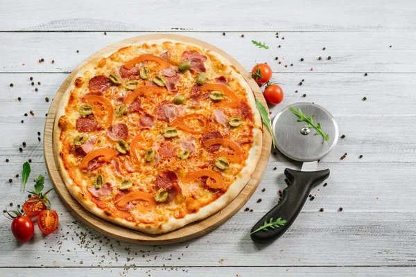 Beyaz ahşap arka planda mozarella, salam ve zeytinli lezzetli pizza Chachatore.